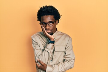 Young african american man wearing casual clothes and glasses thinking looking tired and bored with depression problems with crossed arms.