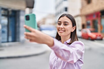 Young hispanic woman smiling confident making selfie by the smartphone at street