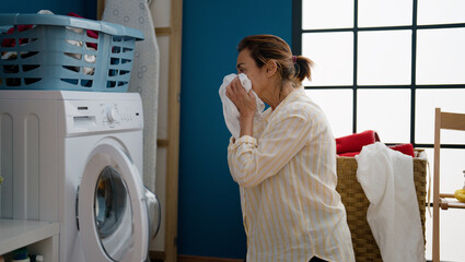 Middle age hispanic woman washing clothes at laundry room