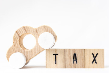 木のブロックのTAXと、玩具の車。税金のイメージ