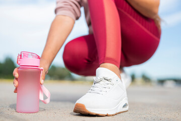 girl athlete runs in the morning in sneakers with a bottle of water