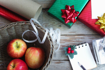 Gift box wrapped in bright green and red paper and note book. It is being prepared for delivery,...