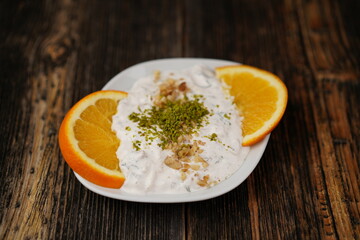 Traditional Turkish and Greek appetizers made labneh cream cheese dip with olive oil, salt, and herbs served with olives in a white bowl appetizer (meze) on a wood background.