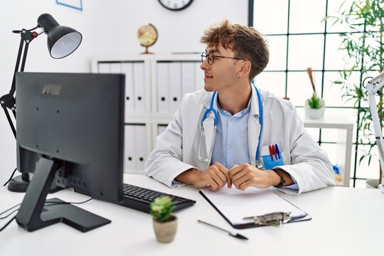 Young caucasian doctor man working at the clinic looking to side, relax profile pose with natural face with confident smile.