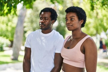 African american man and woman couple standing together with serious expression at park