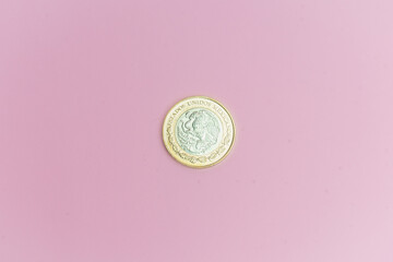 Moneda de 10 pesos mexicanos sobre fondo rosa.