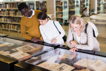 Teacher and adult students view rare books in a library showcase. High quality photo