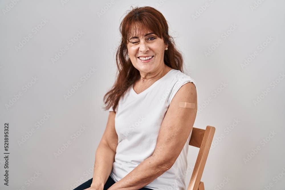 Canvas Prints Middle age hispanic woman getting vaccine showing arm with band aid winking looking at the camera with sexy expression, cheerful and happy face.