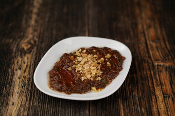 Turkish spicy appetizer (meze) Ezme at wood background. Ezme made with tomatoes, hot chilli, parsley, olive oil and pepper.  Famous traditional Turkish appetizer.