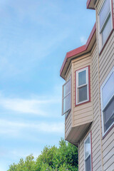 Home exterior in a low angle view with beige vinyl lap sidings against the sky at the background
