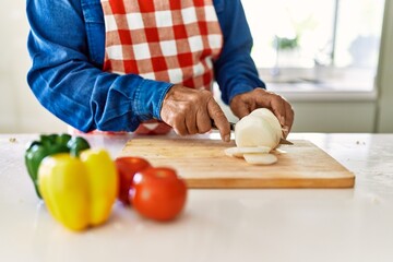Obraz na płótnie Canvas Senior man cutting onion at kitchen
