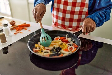 Senior man cooking at kitchen