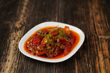 Sun-dried tomatoes in olive oil for an appetizer. Delicious traditional Turkish appetizer (meze). Dry tomatoes with ingredients in olive oil.  