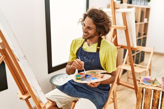 Young hispanic artist man smiling happy drawing at art studio.