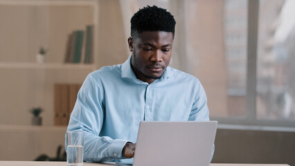 African male busy man worker american businessman guy student sit at home office typing on computer finish online work make daily tasks feel thirsty drink glass of cold fresh water keep health balance