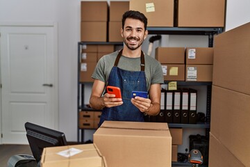 Young hispanic man business worker using smartphone and credit card at storehouse