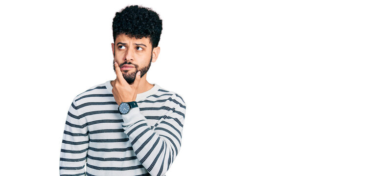 Young arab man with beard wearing casual striped sweater thinking worried about a question, concerned and nervous with hand on chin