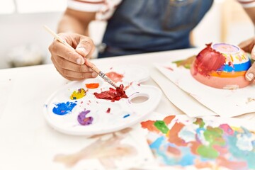 Artist man painting ceramic at art studio.