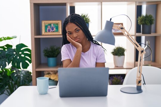 African american woman with braids using laptop at home thinking looking tired and bored with depression problems with crossed arms.
