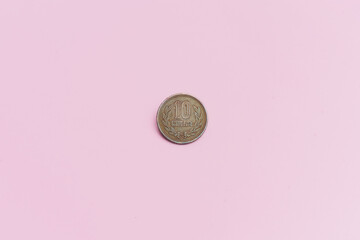 Moneda china de 10 yuanes, sobre un fondo rosa.