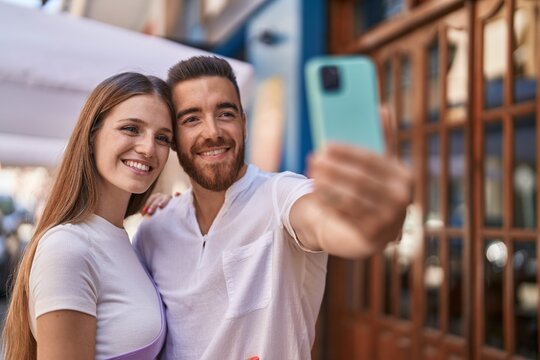 Man and woman couple smiling confident make selfie by smartphone at street