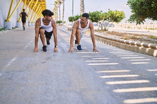 Two hispanic men sporty couple smiling confident on start race position at street