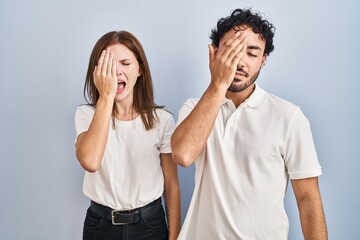 Young couple wearing casual clothes standing together yawning tired covering half face, eye and mouth with hand. face hurts in pain.