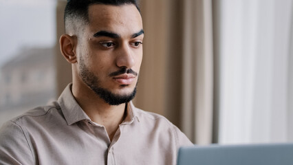 Close-up serious concentrated male portrait arab businessman guy hispanic man freelancer sit at home office texting email on laptop use personal computer wi-fi internet develop new project e-business