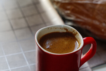 Defocus red cup of coffee. Hot coffee with smoke on old wooden table at coffee shop in the morning. Red mug with foam. Out of focus