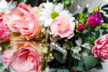 Defocus one golden wedding ring. Pink flowers and two golden wedding rings on white background. wedding rings on the rose. Copy space. Out of focus