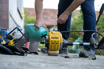 Fototapeta premium adding petrol gas to the gasoline tank of brushcutter string trimmer