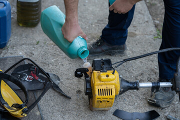 adding petrol gas to the gasoline tank of brushcutter string trimmer