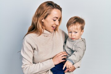 Young caucasian woman holding and hugging her son with love. Family of two bonding together. Mother holding infant toddler