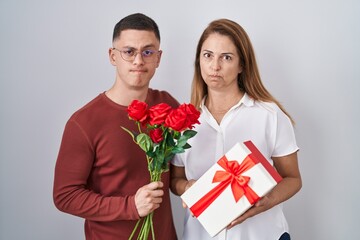 Mother and son holding mothers day gift skeptic and nervous, frowning upset because of problem. negative person.
