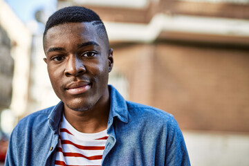 Young african american man with relaxed expression standing at the city.