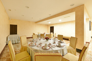Dining table with tablecloth and dinnerware set in a cream room