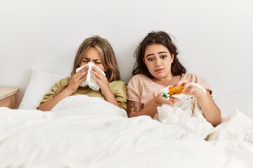 Young ill couple using napkin and eating pills lying on the bed at home.