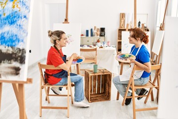 Two artist student women smiling happy painting at art school.