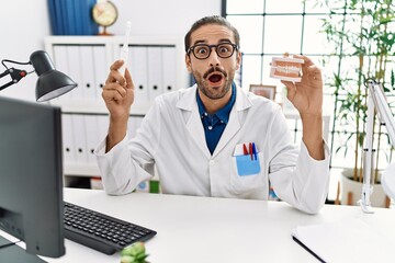 Obraz premium Young hispanic dentist man holding denture and toothbrush celebrating crazy and amazed for success with open eyes screaming excited.
