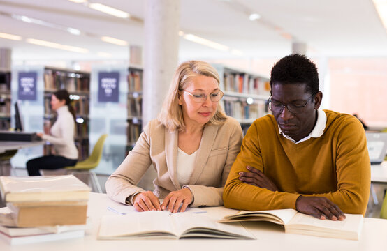 Two adult students studying together in public library. High quality photo