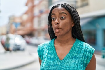 African american woman doing funny gesture with lips at street