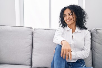 Young hispanic woman smiling confident sitting on sofa at home