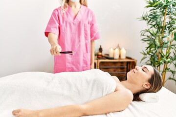 Obraz na płótnie Canvas Young hispanic woman having incense aromatherapy at beauty center.