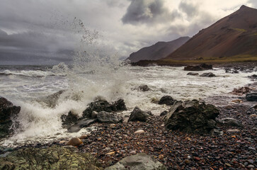 A foamy wave splashes against the shore in Iceland.