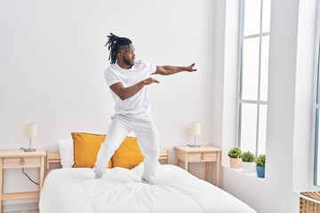 African american woman standing on bed dancing at bedroom