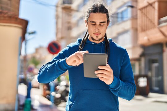 Young man using touchpad with serious expression at street