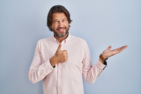 Handsome middle age man wearing elegant shirt background showing palm hand and doing ok gesture with thumbs up, smiling happy and cheerful