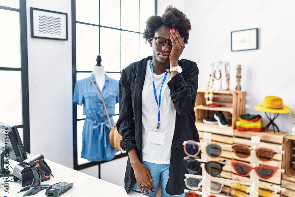 Poster African young woman working as manager at retail boutique yawning tired covering half face, eye and mouth with hand. face hurts in pain.