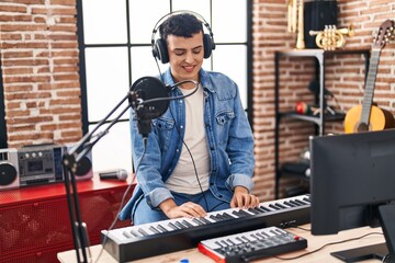 Young non binary man musician singing song playing piano keyboard at music studio