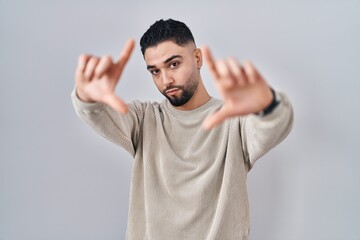 Young handsome man standing over isolated background doing frame using hands palms and fingers, camera perspective